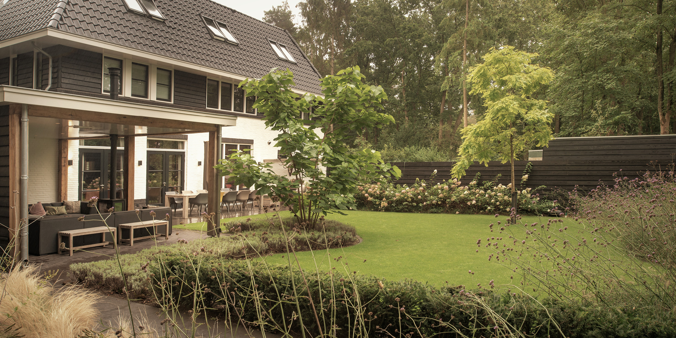 Buytengewoon tuin in Zeist met gazon, veranda en zithoek.