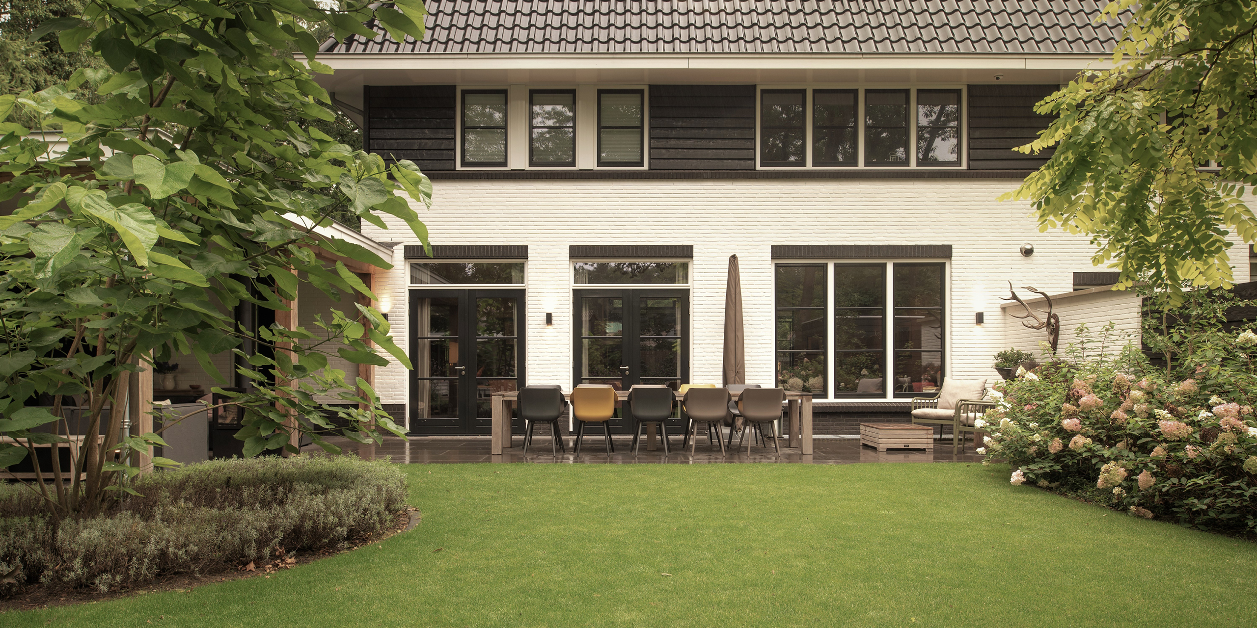 Buytengewoon tuin in Zeist met gazon, terras, tuintafel en veranda.