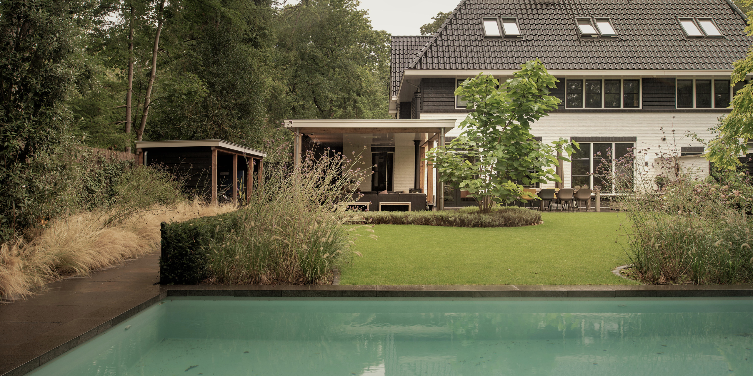Buytengewoon tuin in Zeist met zwembad, gazon, taxushaag, bomen, berging, veranda, terras en zithoek.